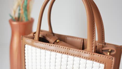 cerrado de un bolso de cuero marrón claro con un detalle tejido blanco