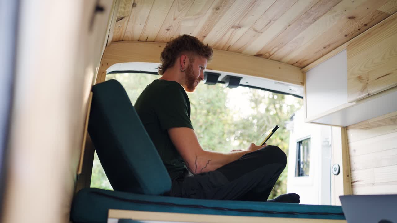 Man relaxing inside a campervan with wooden interior