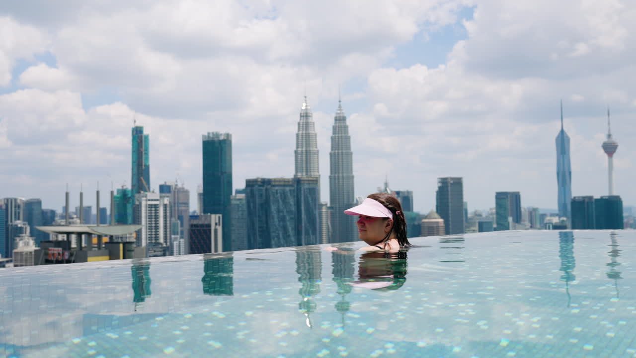Mujer disfrutando de las vistas de torres icónicas desde una piscina infinita en Kuala Lumpur, Malasia
