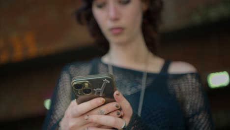 close up outdoor fashion shot of young alternative style woman using mobile phone on london city street uk in real time