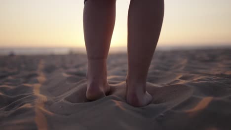 closeup tracking follow of woman in dress walking towards sunset on sandy beach