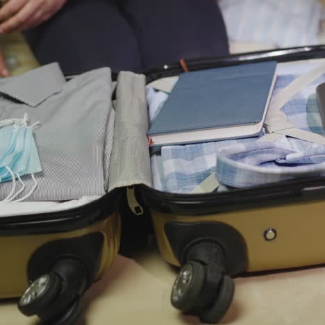 a woman packs clothes and face mask for a business trip 3