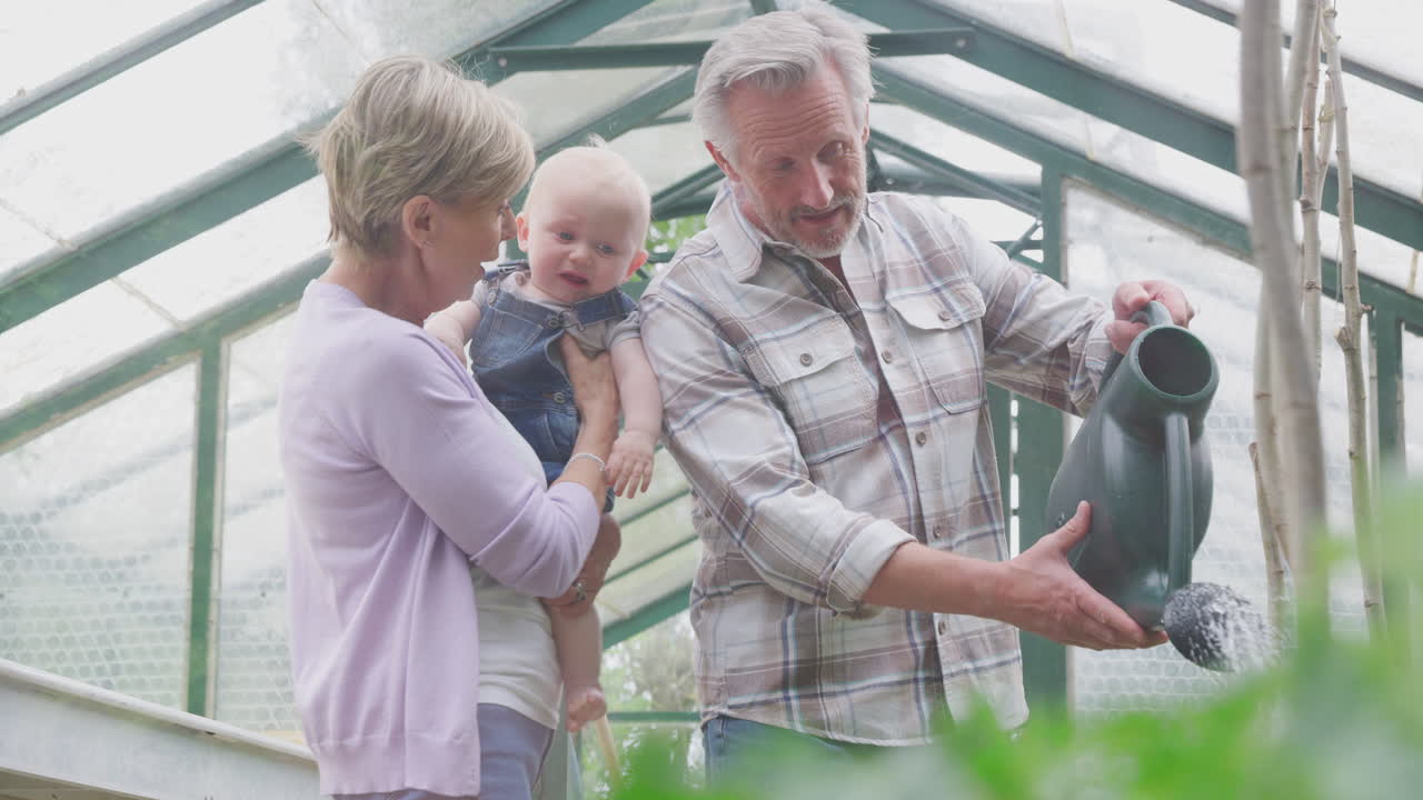 abuelos con nietos bebés regando plantas en el invernadero juntos