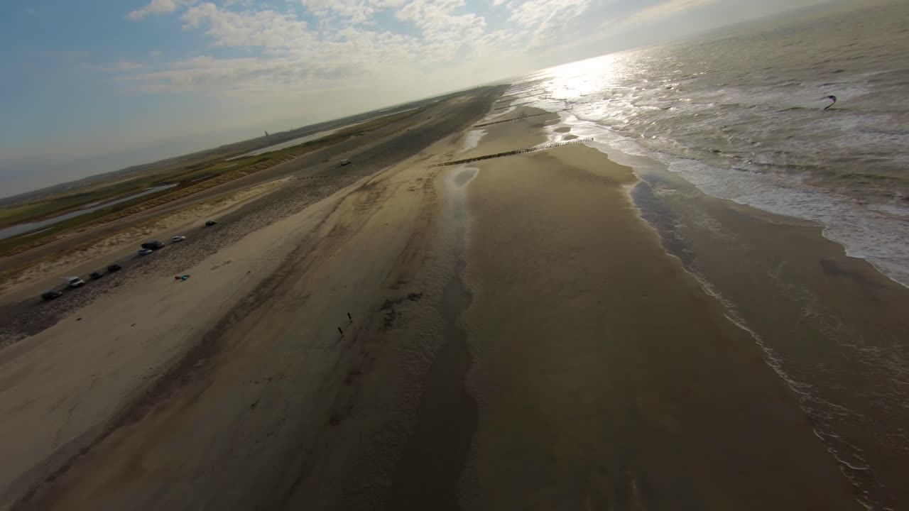 Aerial drone flight over beach and kite surfers riding ocean waves in Domburg