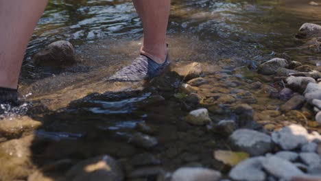 a person crosses the mountain stream, closeup on the feet