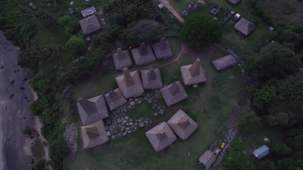 Abitanti del luogo in un pittoresco villaggio con tetti unici all'alba, Sumba, Indonesia