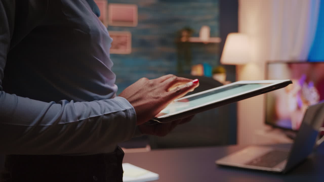 Close-up photo of black female hands holding tablet and typing