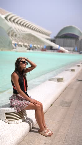 woman relaxing by a fountain in front of a modern building