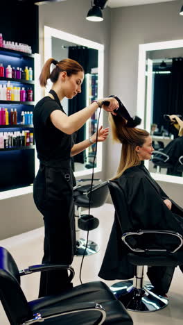 hairstylist blow-drying client's hair in a salon