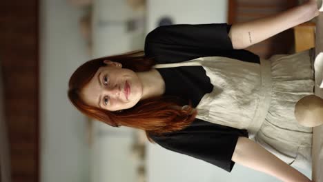 the red-haired girl potter smiles, her products are near her against the background of the workplace