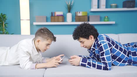 dos hermanos pasando el tiempo con el teléfono y la tableta.