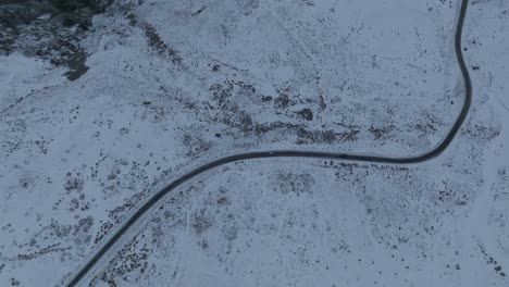 Top-down-tracking-shot-of-a-car-driving-alone-along-a-road-in-the-Andean-Mountains