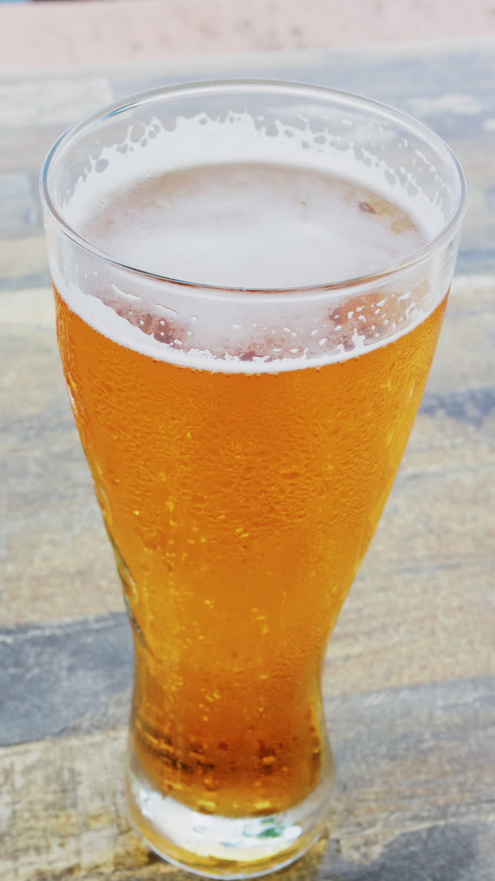 Close up of bubbles forming into foam in a beer glass. Vertical