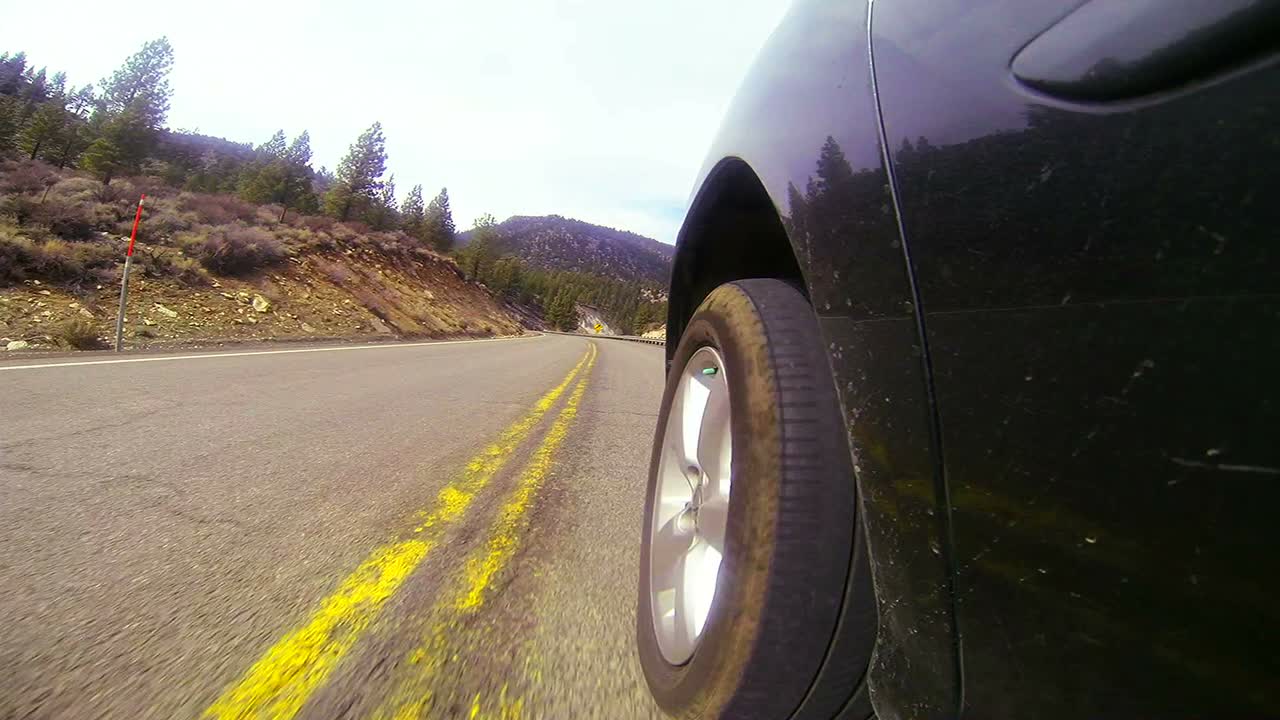 tiro pov conduciendo por una carretera con el lado del coche y la rueda visibles