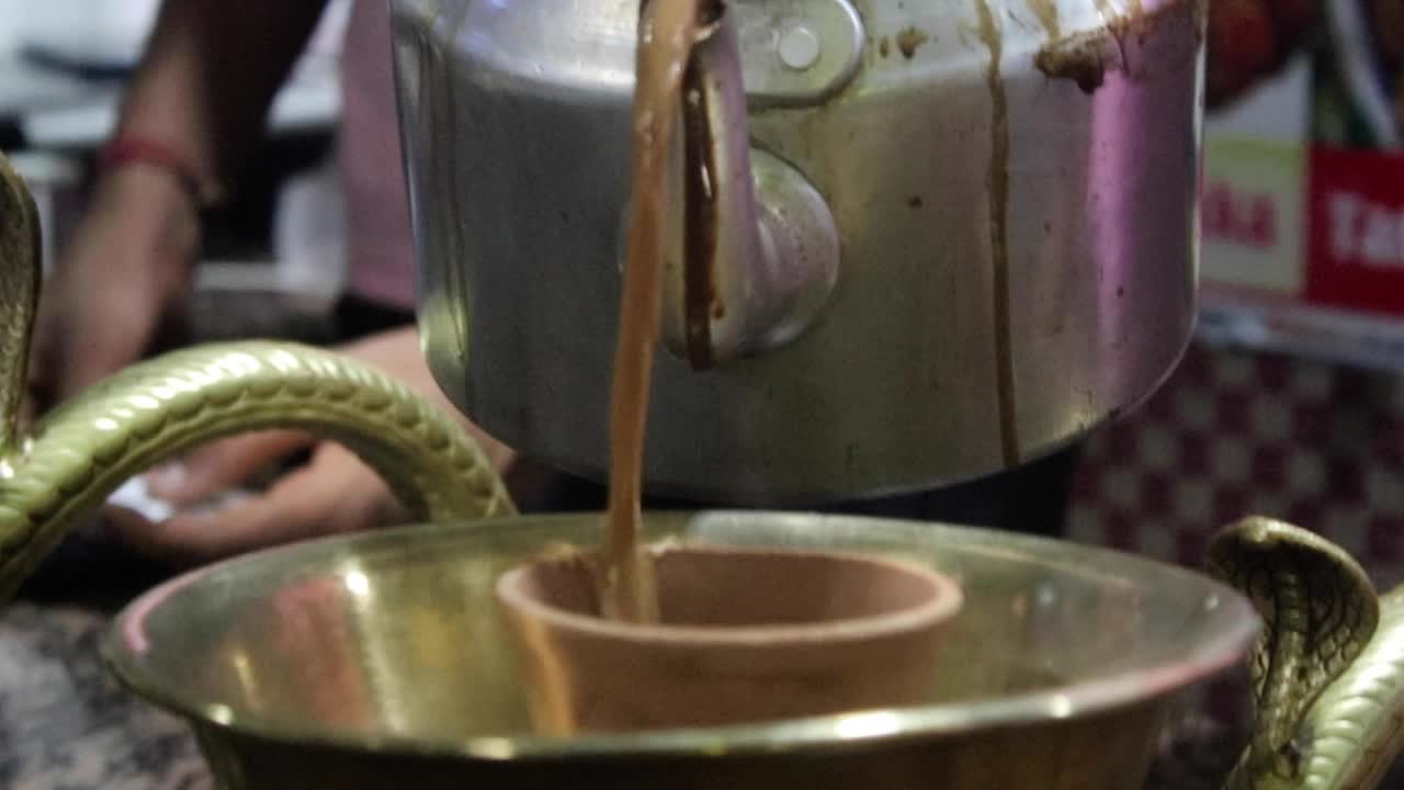 Close Up Of Hot Indian Tandoori Tea Being Poured Into Clay Cup. Follow Shot