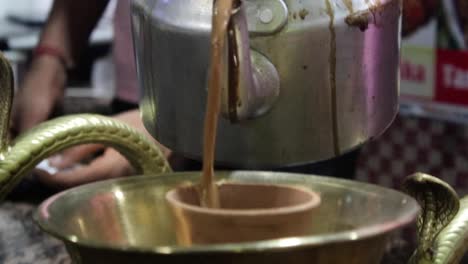 close up of hot indian tandoori tea being poured into clay cup. follow shot