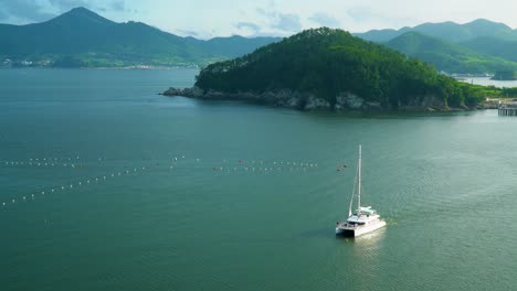 Yate-De-Catamarán-De-Vela-En-El-Sereno-Paisaje-Marino-Cerca-De-Hanwha-Resort-Geoje-Belvedere,-Isla-De-Geoje,-Corea-Del-Sur