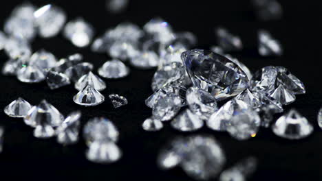 toma macro en cámara lenta de diamantes reales brillantes de varios tamaños arrojados sobre la mesa de clasificación negra en una joyería para un examen más detallado