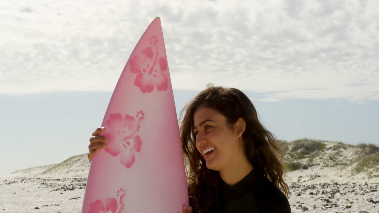 mujer de pie en la playa con tabla de surf 4k