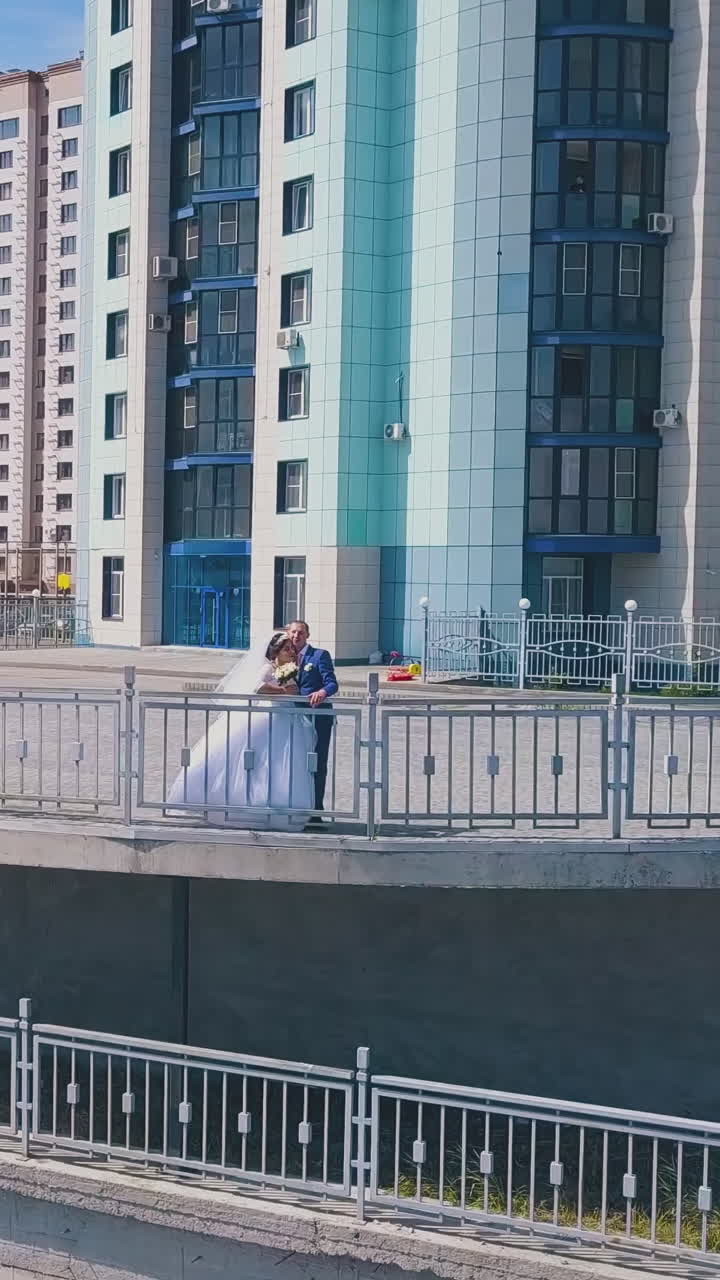 happy bride in white dress with groom on observation deck against modern city on nice sunny day upper view