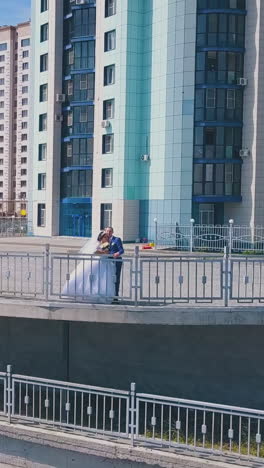 happy bride in white dress with groom on observation deck against modern city on nice sunny day upper view