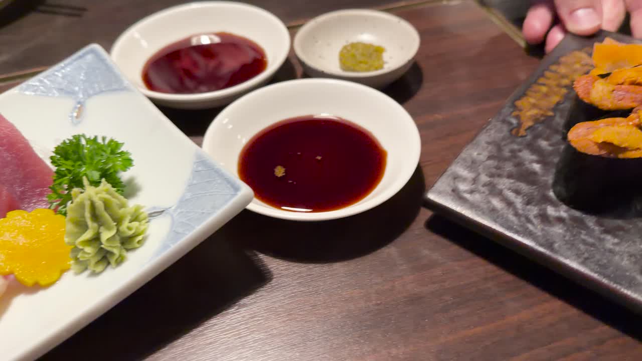 Fresh sashimi and uni sushi on plates, served with soy sauce under warm restaurant lighting