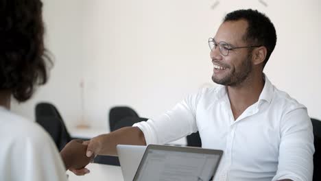 empleado alegre hablando y estrechando la mano con los clientes