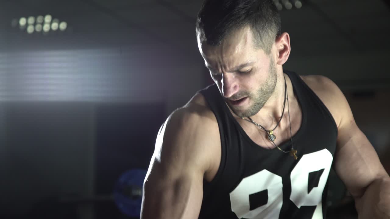 Brutal man shakes his biceps in the gym