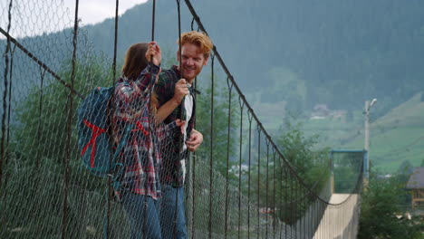 positives paar steht an einer brücke in den bergen. zwei wanderer sprechen draußen miteinander.