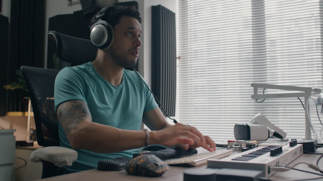 Man adjusting headphones and using computer keyboard in a cozy music studio