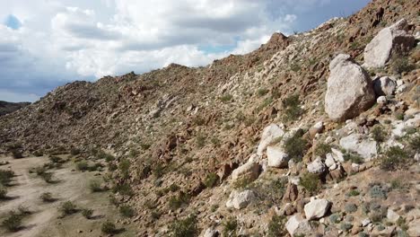 drone shot panning up side of colorful, rocky hill