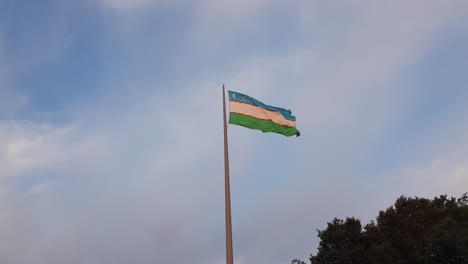 National-Flag-of-Uzbekistan-Waving-on-Pole-on-Windy-Day-at-Golden-Hour-Sunlight