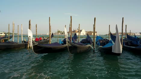 Wide-shot-of-traditional-venice-gondolas-rocking-on-the-waves-and-San-Giorgio-church