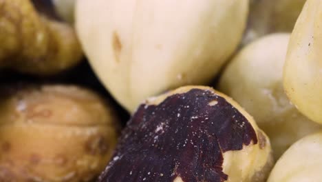 foto macro de una mezcla de frutos secos: avellanas, almendras, nueces girando sobre una superficie negra