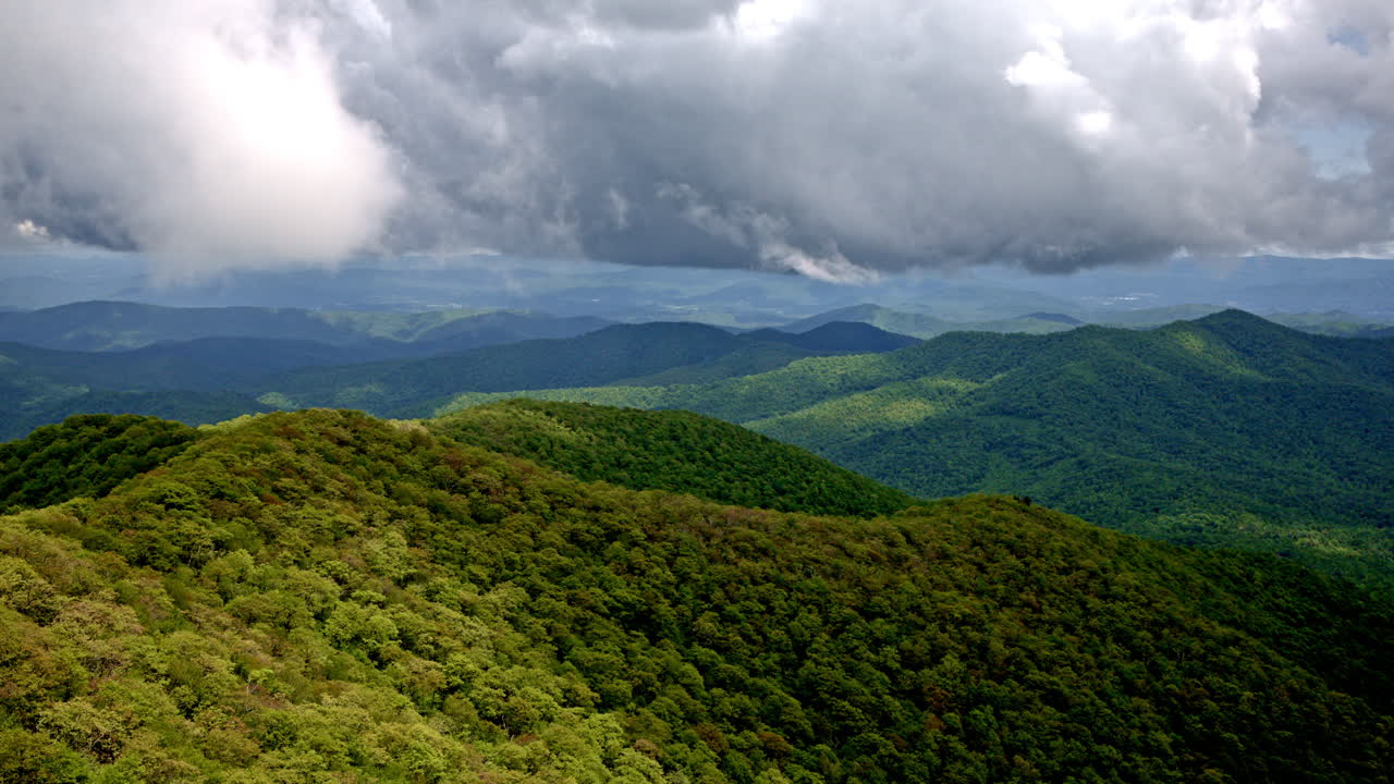Dramatic drone shot flying over vast smoky mountain wilderness with fog, mist and rain adding to the atmosphere