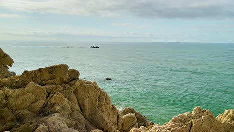 Mediterranean-beach-without-people-at-sunrise-turquoise-blue-calm-water-Barcelona-coast-Maresme-Costa-Brava-Spain-European-tourism-sliding-shoot-rocks-and-fishing-boat