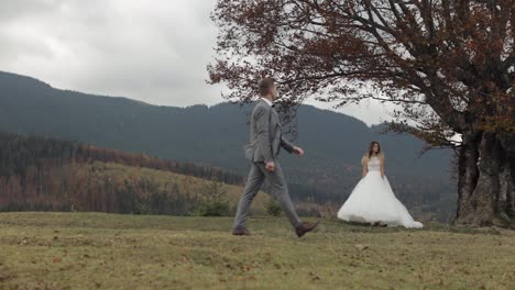 Lovely-caucasian-wedding-couple-newlyweds-family-bride-groom-stay-together-on-mountain-slope-hill