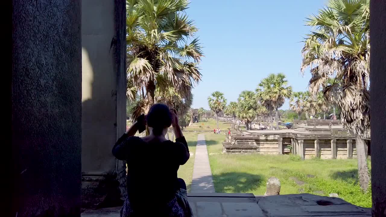 Tourist sitting at Angkor Wat, Siem Reap Cambodia, rear view