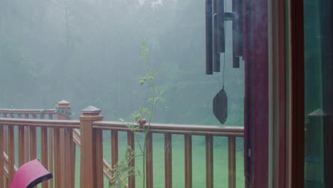 rain on porch with windchimes and tomato plant