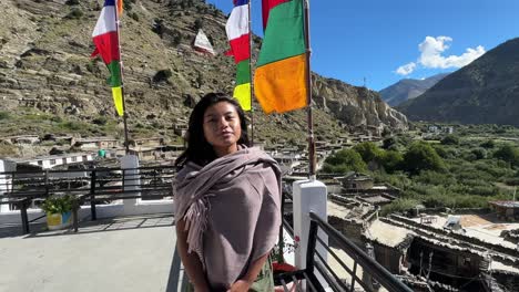 joven asiática de pie en el techo de un hotel en el pueblo de marpha con majestuosas montañas nepalesas en el fondo - cámara lenta