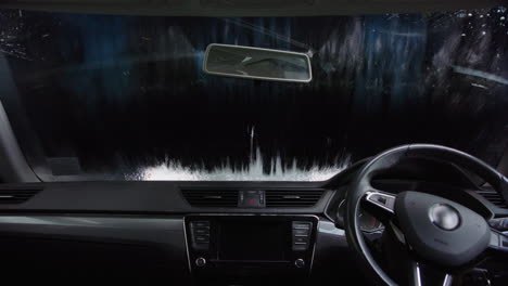 interior cabin pov of rotating brush washing windshield at automated car wash