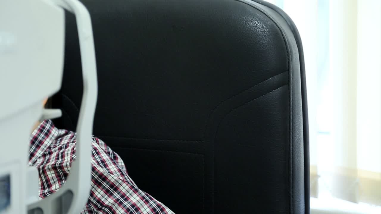 Little boy checks eyesight in modern ophthalmological clinic. Eye examination