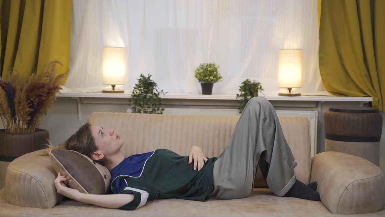 소파에 누워 있는 젊은 여성이 휴식을 취하고 있습니다.