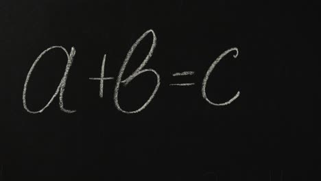 hand writing a mathematical equation on a blackboard