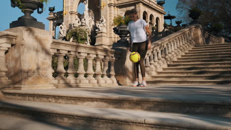 una mujer deportiva caucásica haciendo kick ups con la pelota al aire libre.