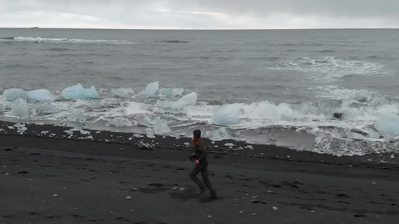 차가운 해변을 따라 달리는 젊은 남자를 따라 공중 촬영