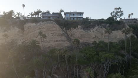 daylight, sunset, drone footage looking over cliff with houses over city