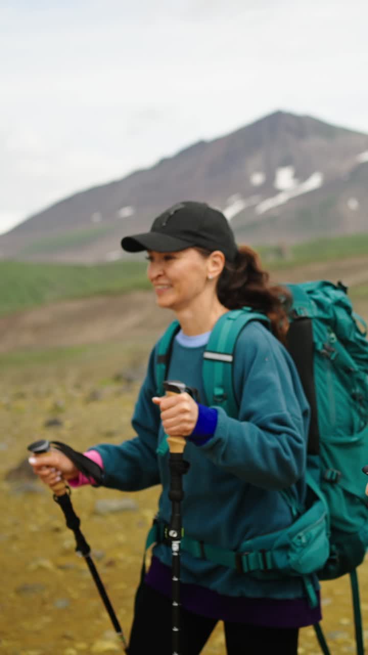 Donna che fa escursioni con zaino e bastoncini da trekking in un paesaggio montano