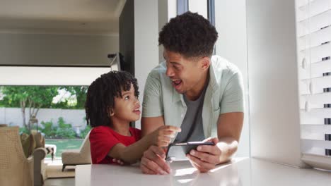 Hombre-Birracial-Feliz-Y-Su-Hijo-Usando-Un-Teléfono-Inteligente-Juntos