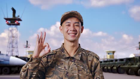 smiling soldier in camouflage uniform giving ok sign at airbase